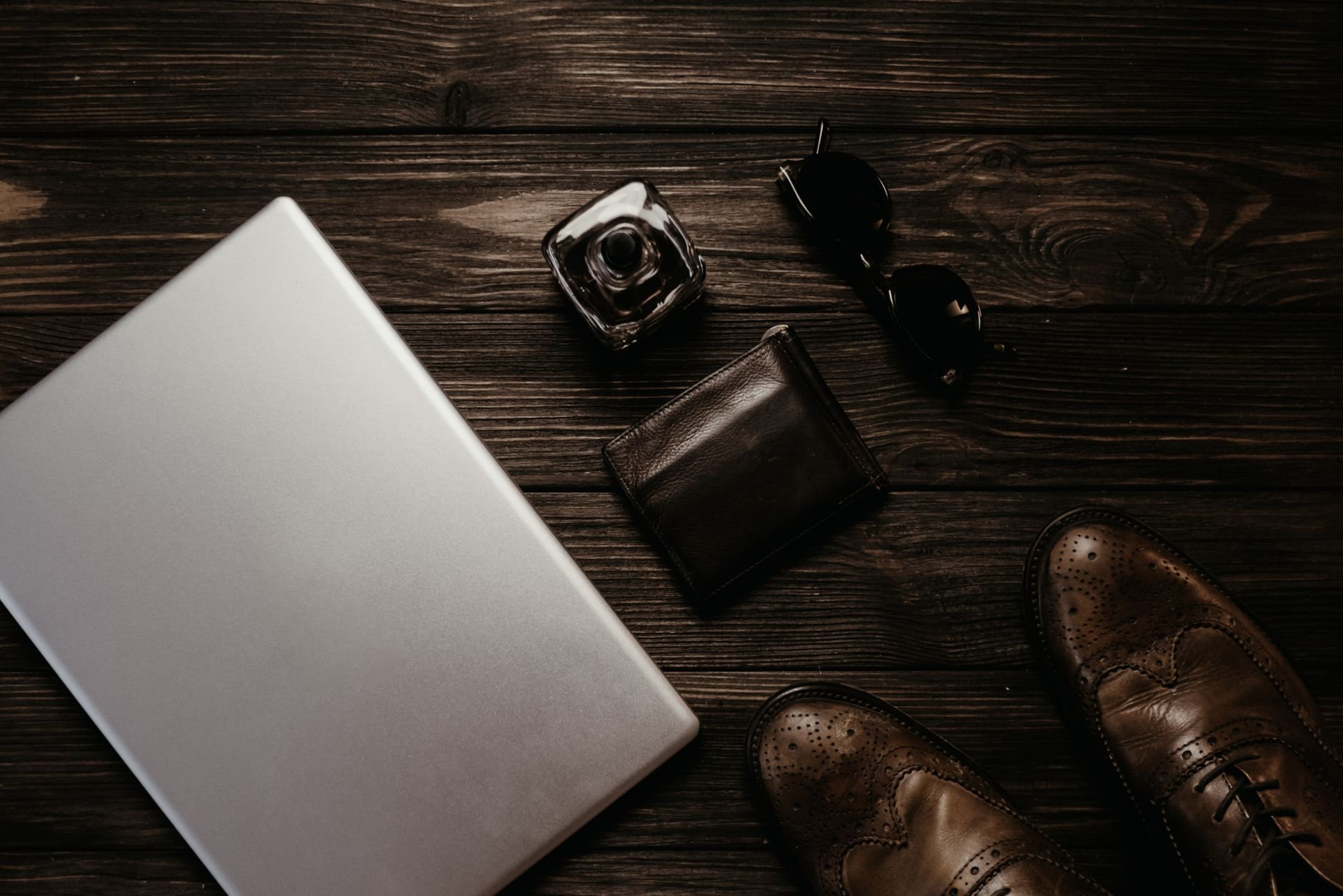 Flat lay of premium leather goods and stylish accessories on a wooden surface.